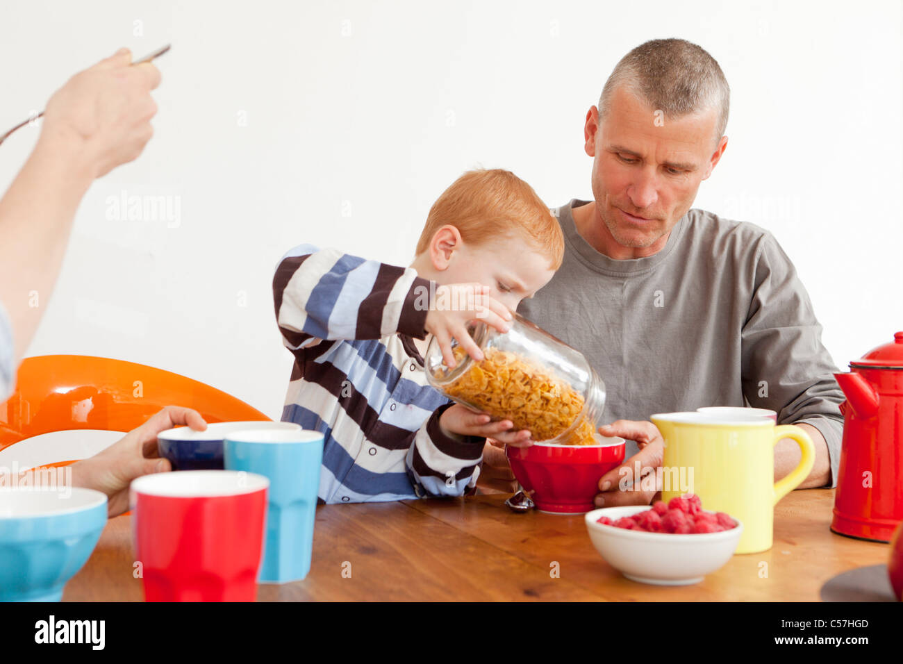 Boy pouring father bowl of cereal Stock Photo Alamy