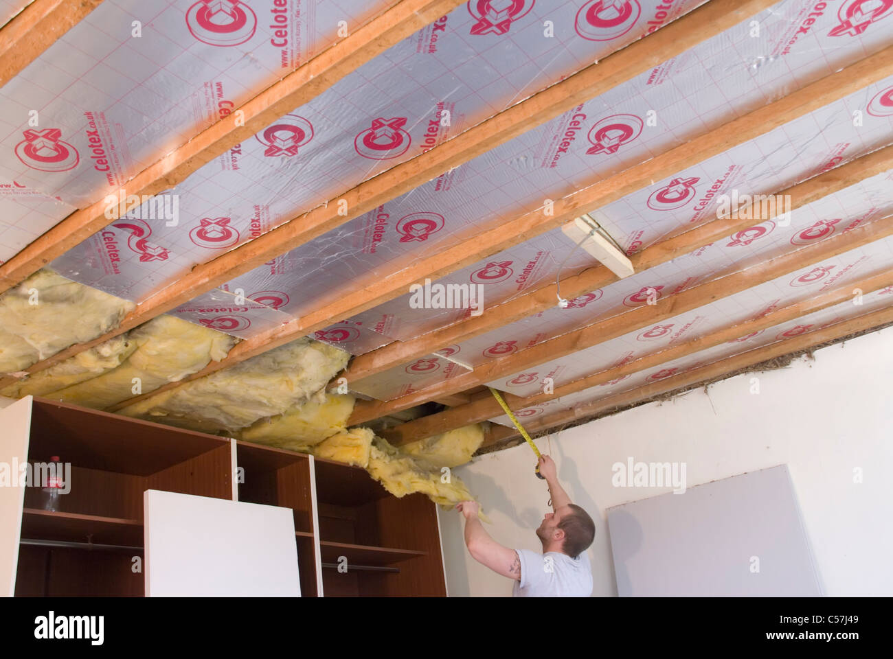 Builders installing high performance Kingspan Therma and Celotex insulation boards to the walls and ceiling of an older house Stock Photo