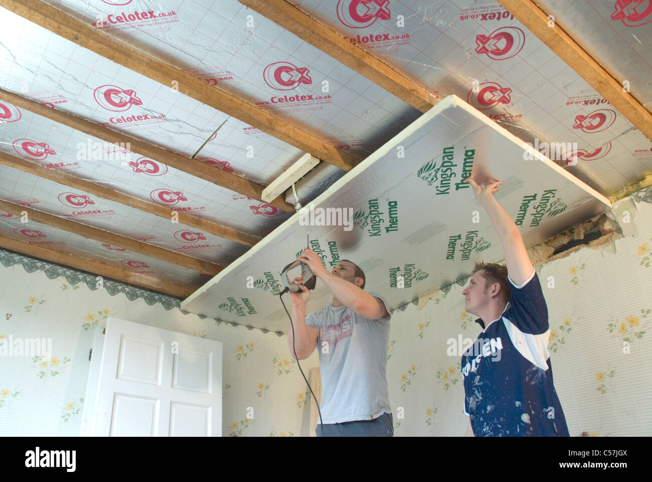 Builders installing high performance Kingspan and Celotex thermal insulation boards to the walls and ceiling of an older home Stock Photo