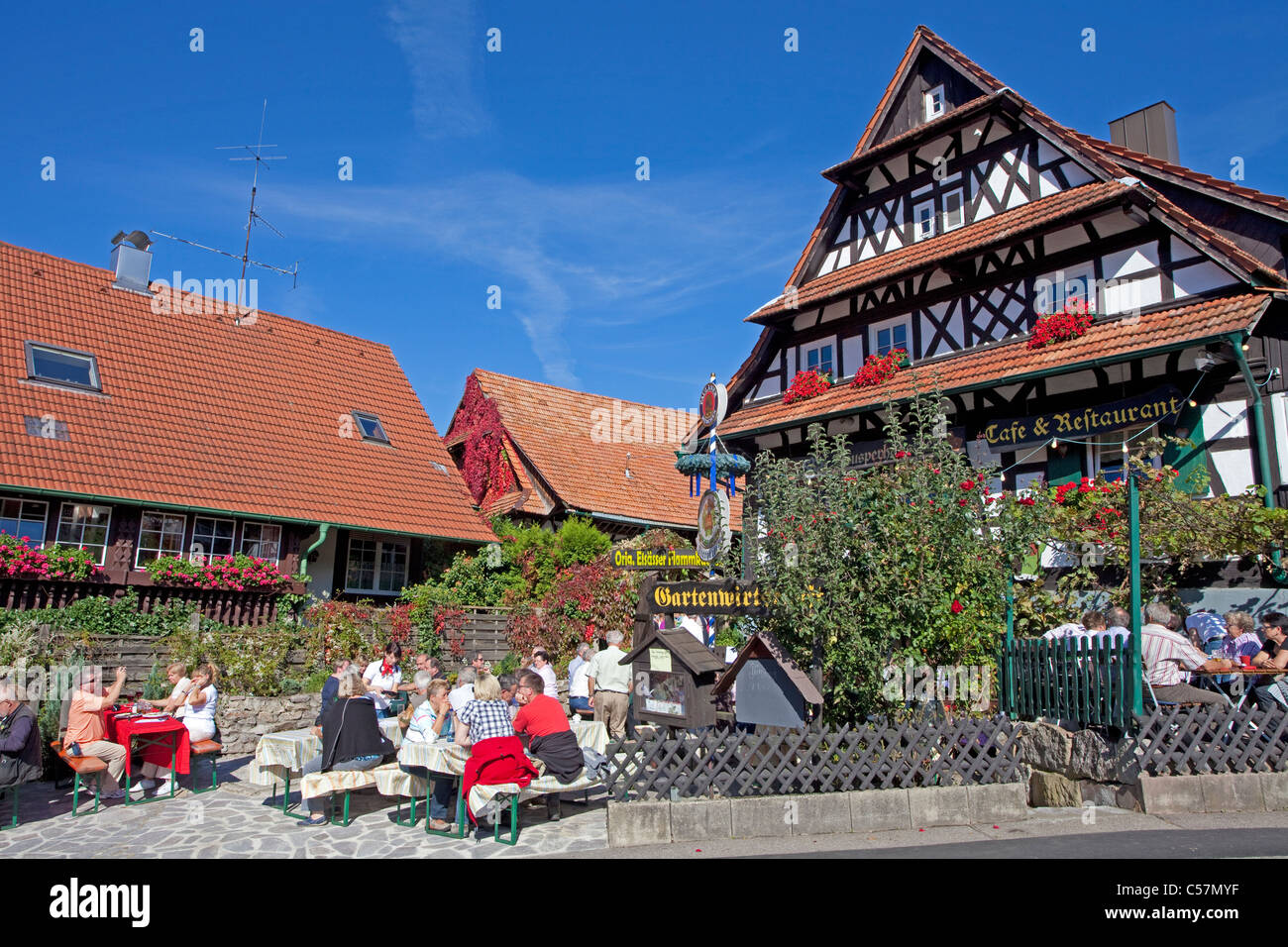 People in a garden restaurant, half-timbered house, flower decoration, Sasbachwalden, North Black forest, Black forest, Baden-Wuerttemberg, Germany Stock Photo