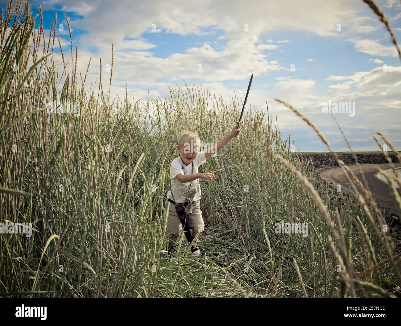 Boy playing with sword in wheat field Stock Photo