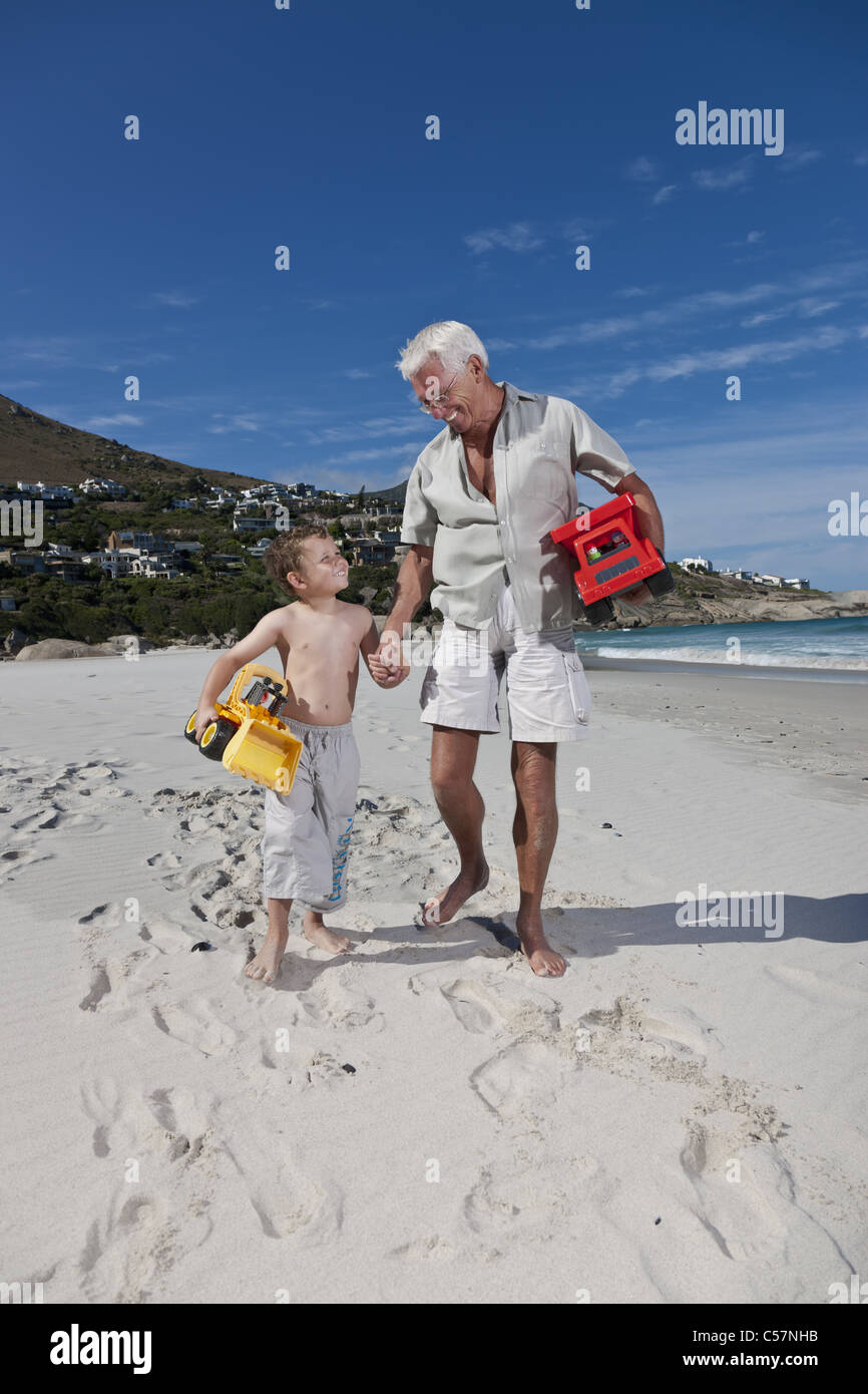 Man holding grandson’s hand on beach Stock Photo