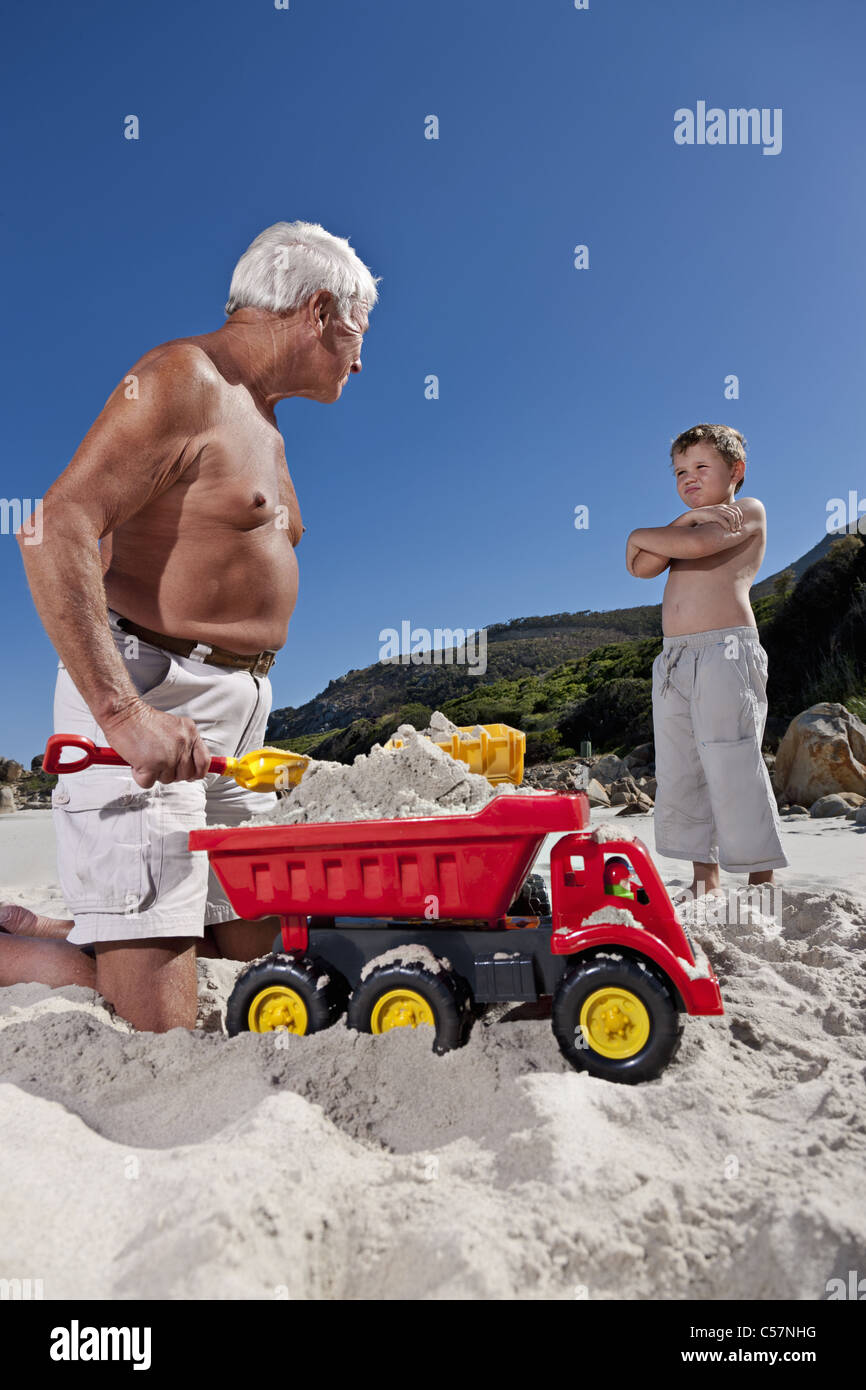 Man playing with grandson on beach Stock Photo