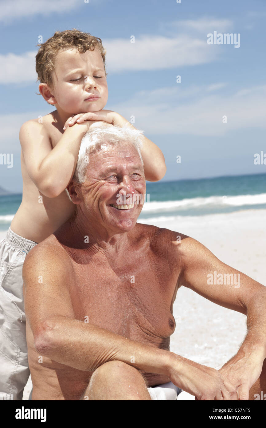 Older man with grandson on beach Stock Photo