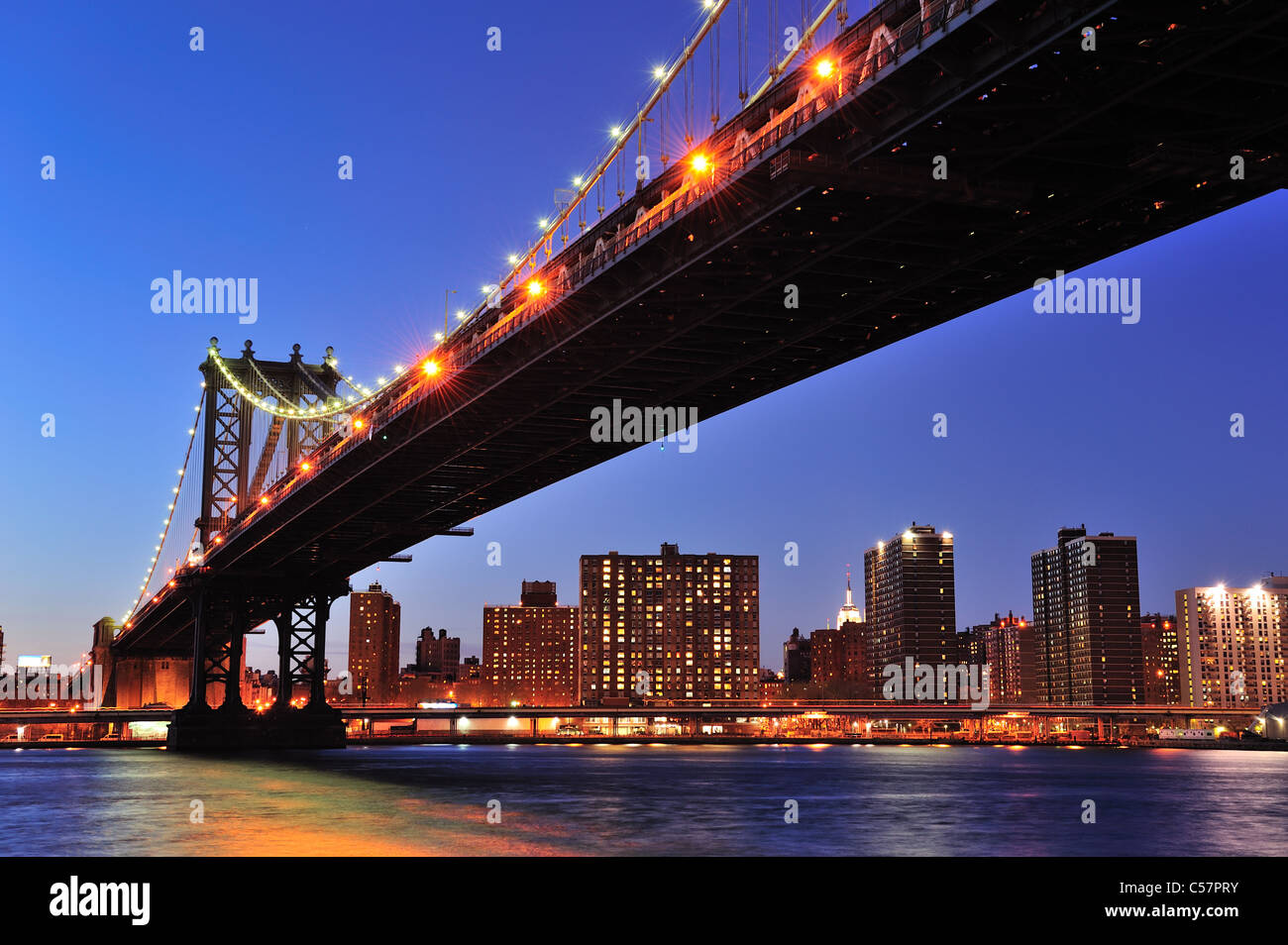 New York City Manhattan Bridge over East River at dusk illuminated with ...