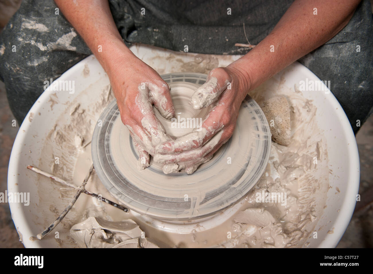 Female ceramicist using a Potter's wheel to work on a ceramic piece in