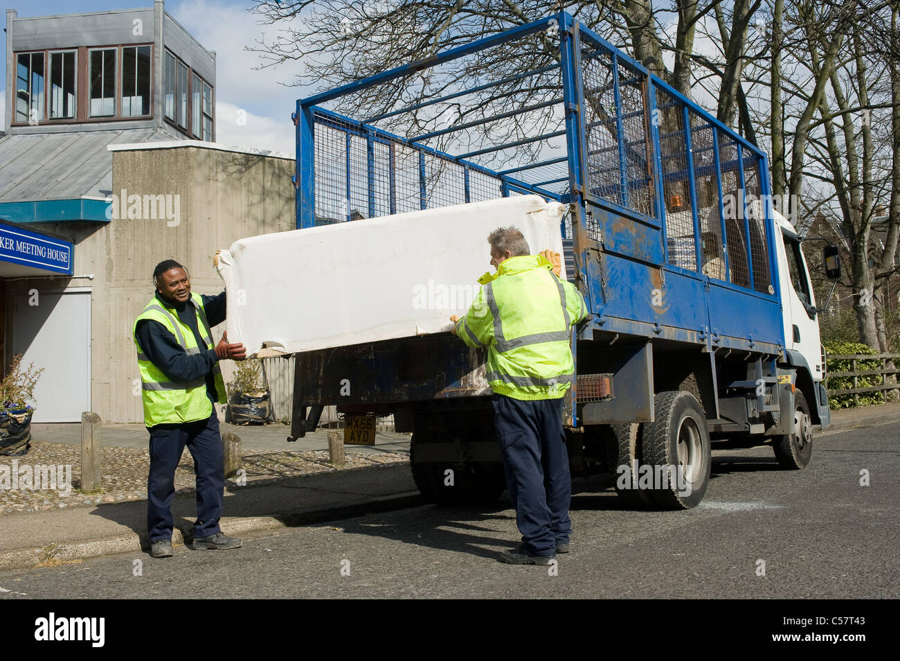 Council workers collecting old furniture and loading it into a truck