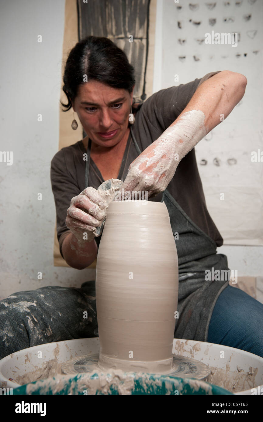 Female ceramicist using a Potter's wheel to work on a ceramic piece in
