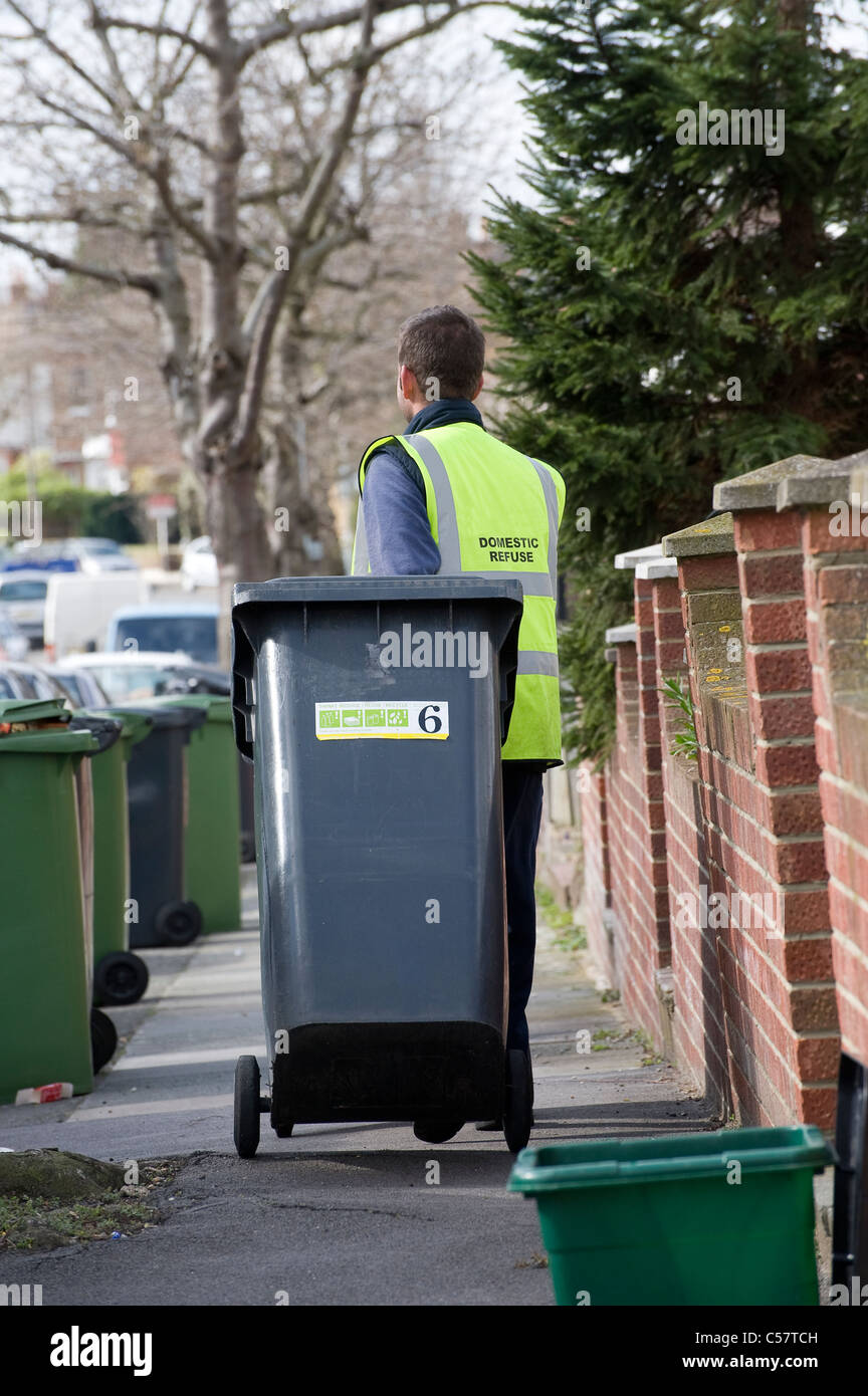 Bin man collecting wheelie bins on a housing estate in England Stock
