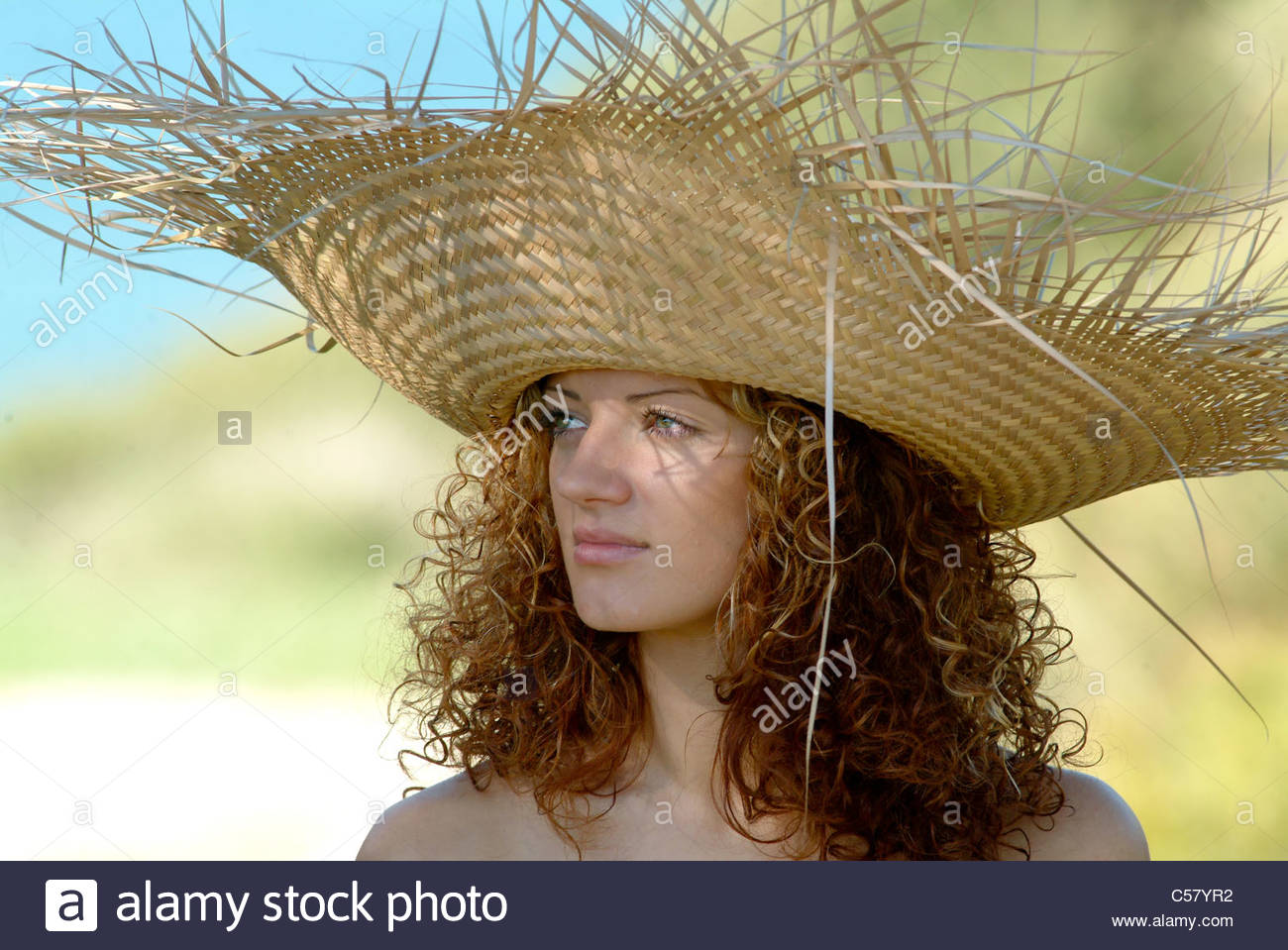 Young Woman With Long Curly Hair Wearing Large Straw Hat At The
