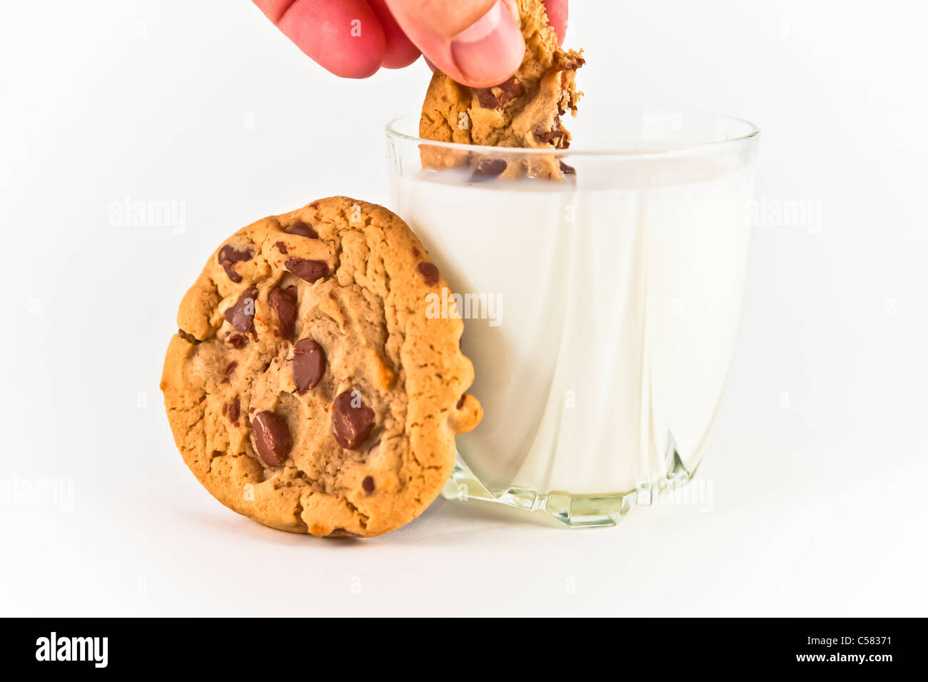 Dunking cookie in milk. Stock Photo