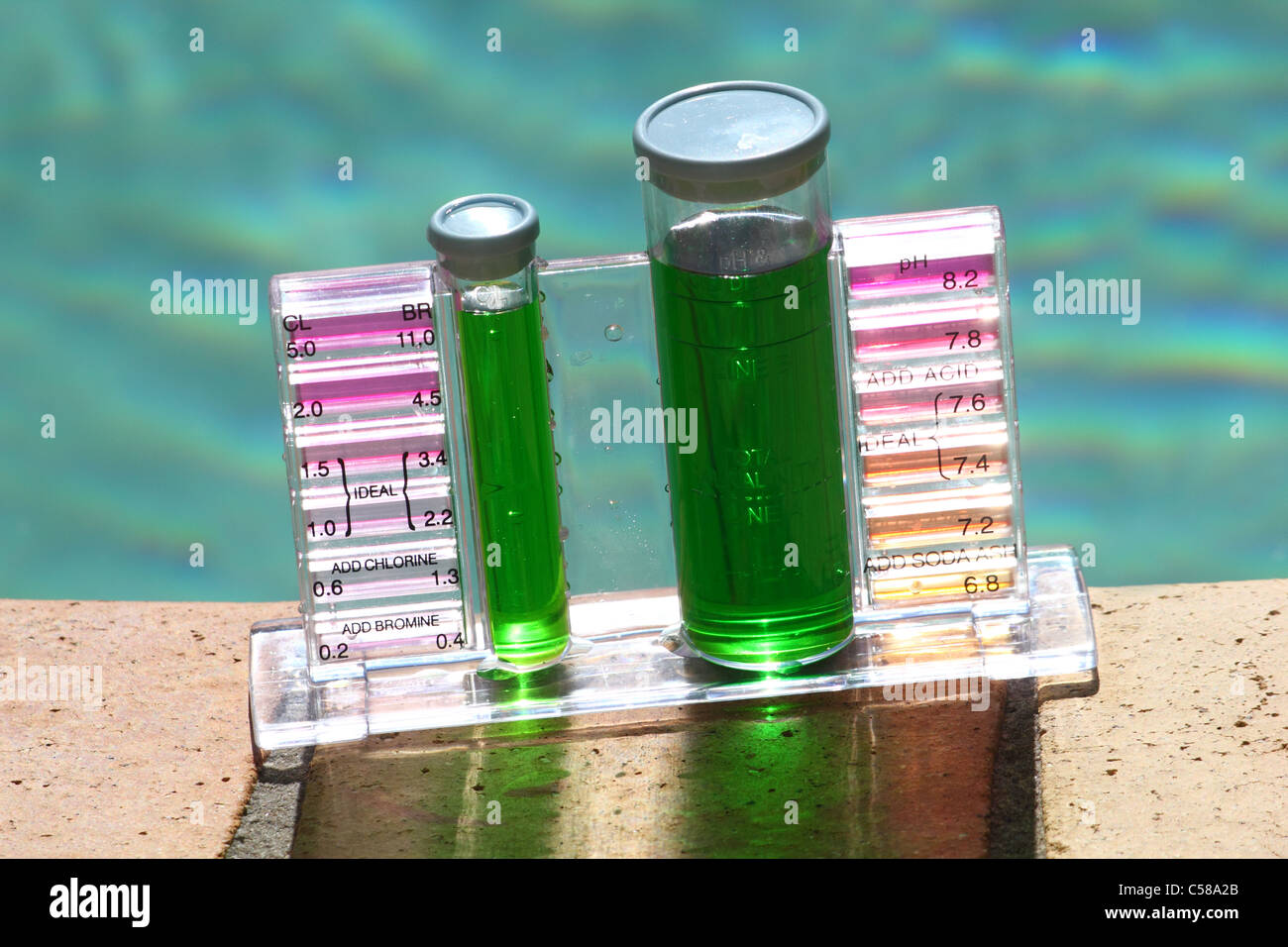 SAMPLE OF SLIMY GREEN WATER IN A POOL TEST KIT BLUE SKY AND POOLSIDE BACKGROUND HORIZONTAL BDB