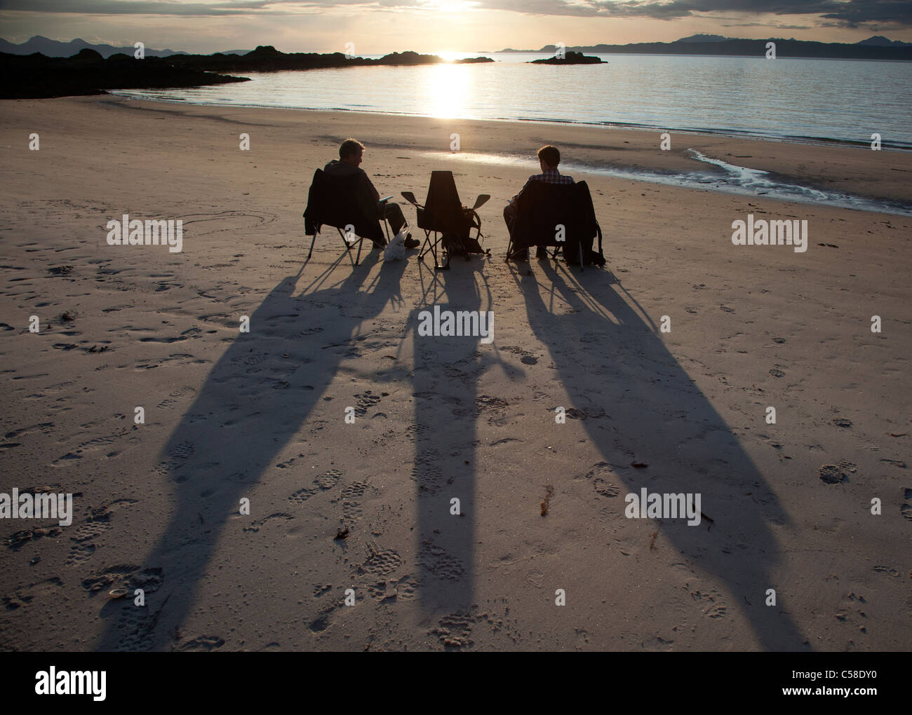 Two men sitting on chairs watching the sunset on a Scottish beach, Scotland, UK Stock Photo