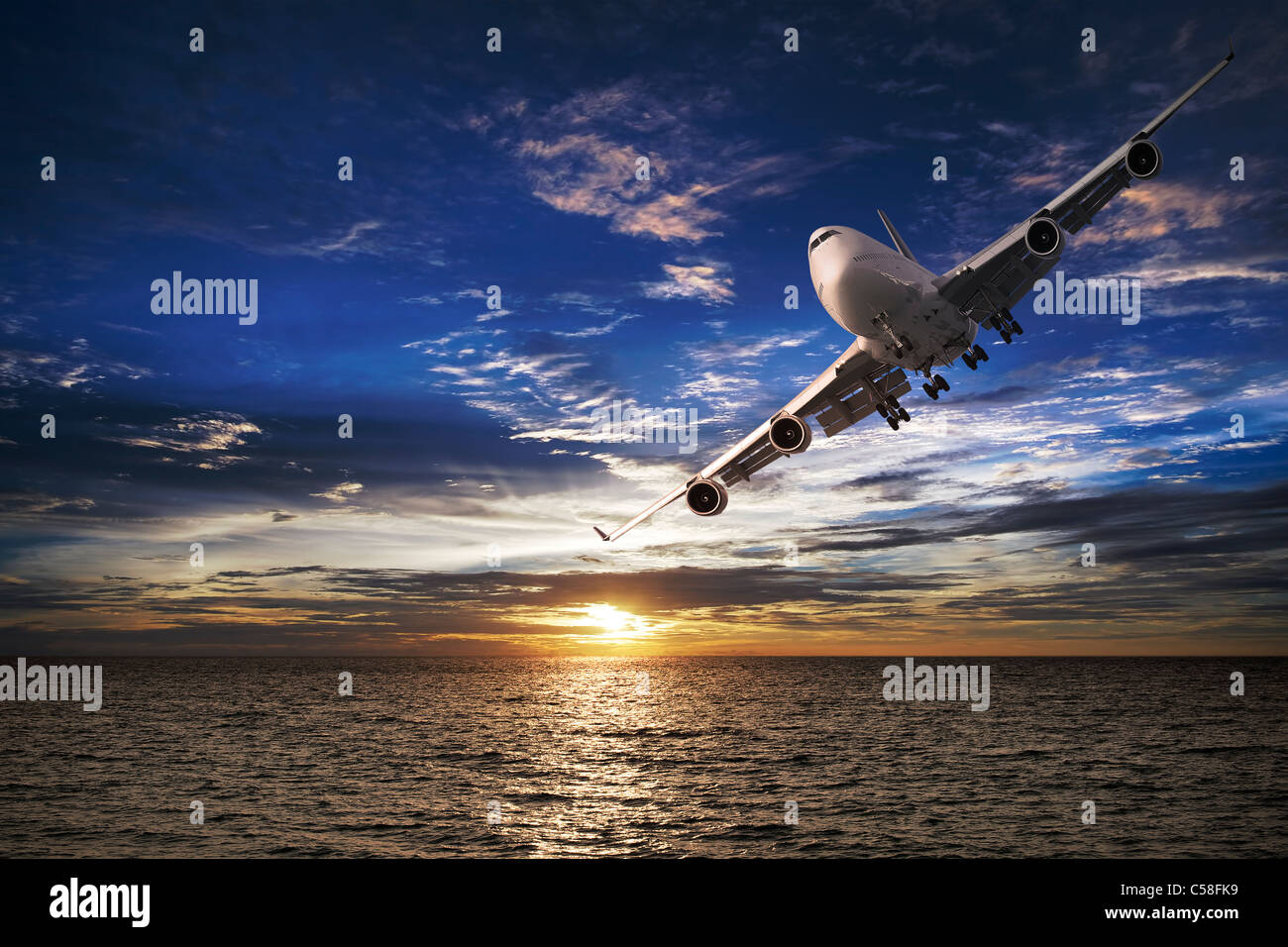 Jet plane over the sea at sunset time Stock Photo