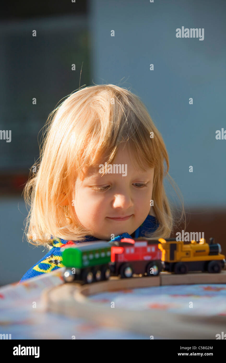 blond, boy, child, childhood, concentrated, close, cute, fun, garden, kid, hair, looking, outdoor, outdoors, play, toy, train Stock Photo