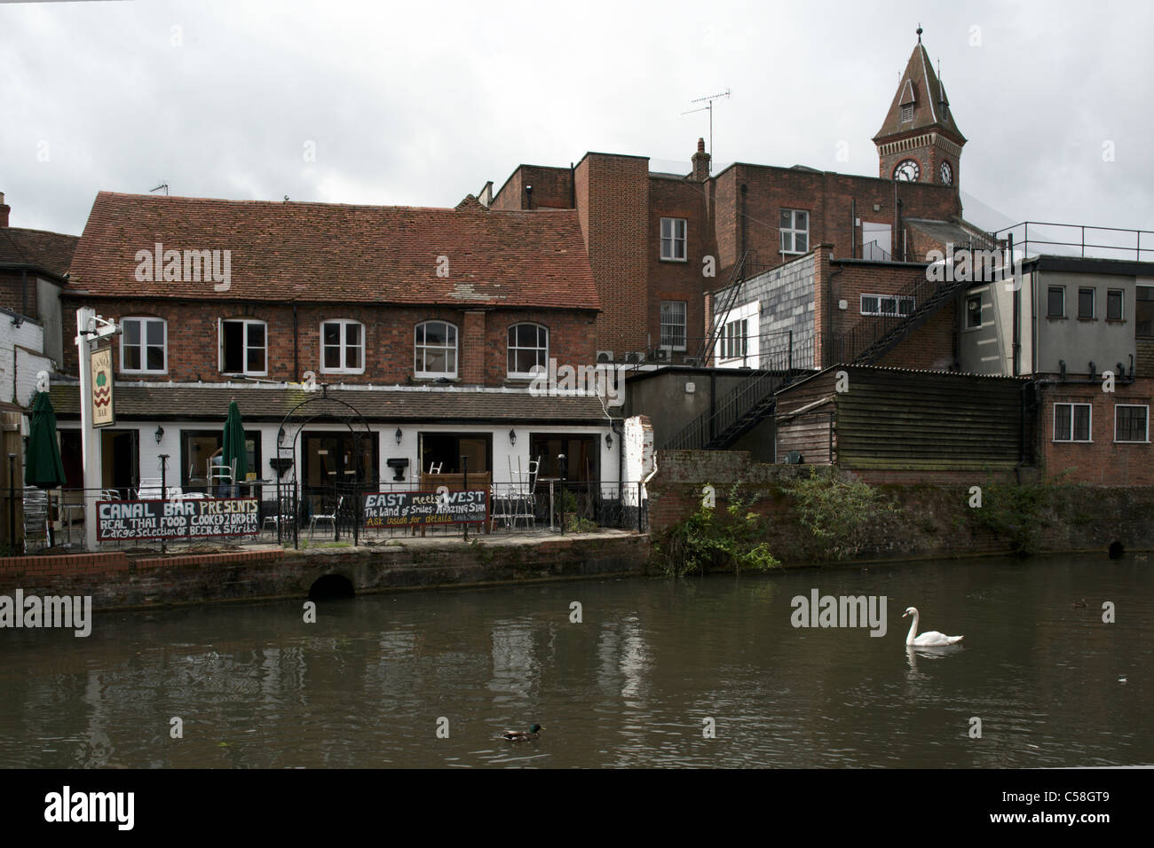 East and West pub bar Kennet and Avon canal side Newbury Berkshire England UK with swan town hall clock tower in the background Stock Photo