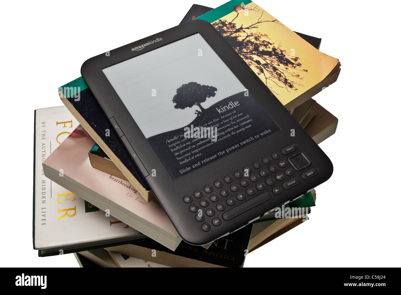 An Amazon Kindle ereader on top of a large stack of assorted books and