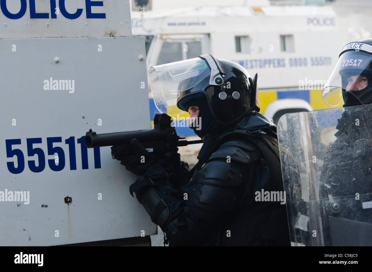 Police officer aims a Heckler and Koch L104A1 37mm single-shot AEP launcher at rioters Stock Photo