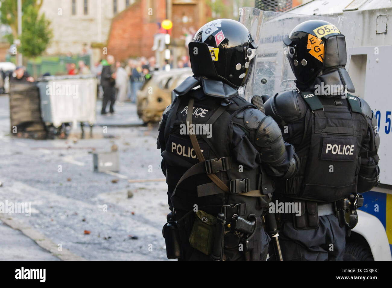 Police officers in riot gear at a riot gear watch group of rioters Stock Photo