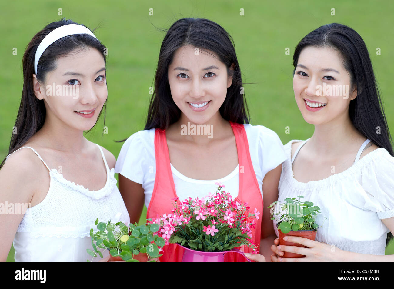 Portrait of young women holding potted plant Stock Photo - Alamy