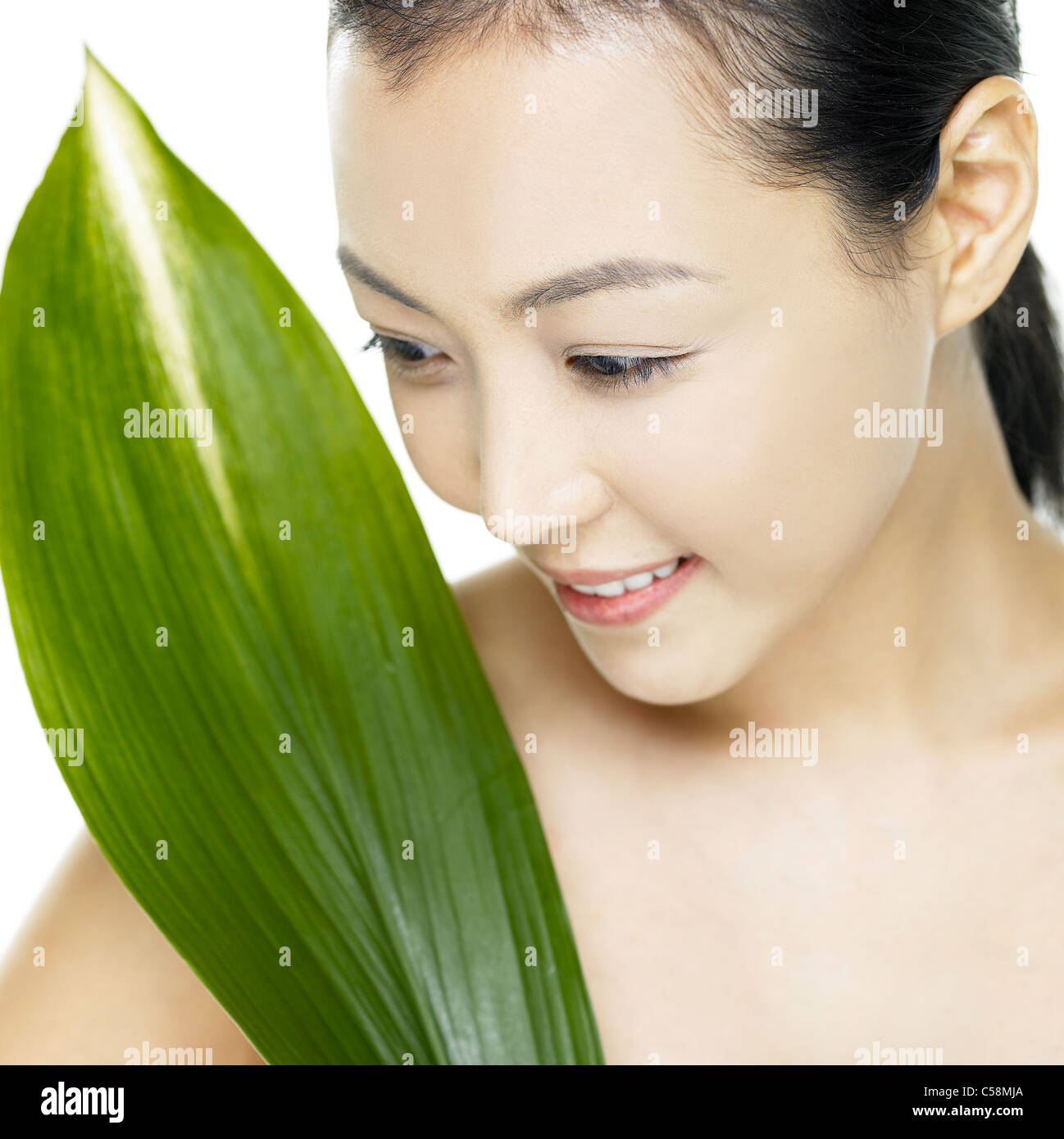 Close-up of young woman with leaf on face Stock Photo - Alamy