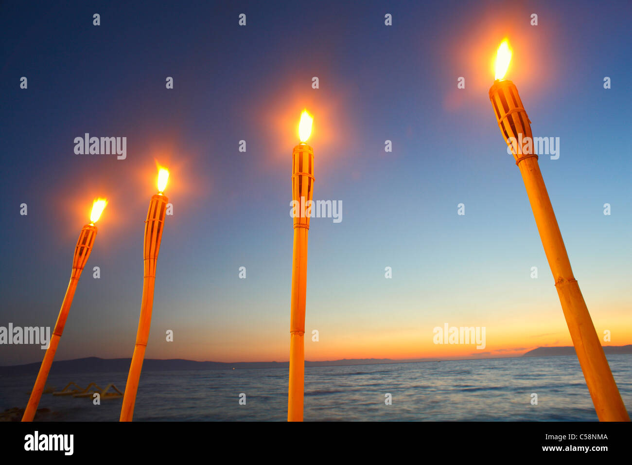 Four fire torches at sunset Stock Photo