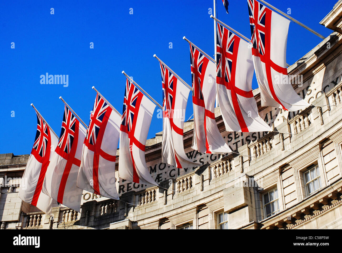 Royal Navy white ensign flags flying from Admiralty Arch in London, UK, on a sunny Summer day. Stock Photo