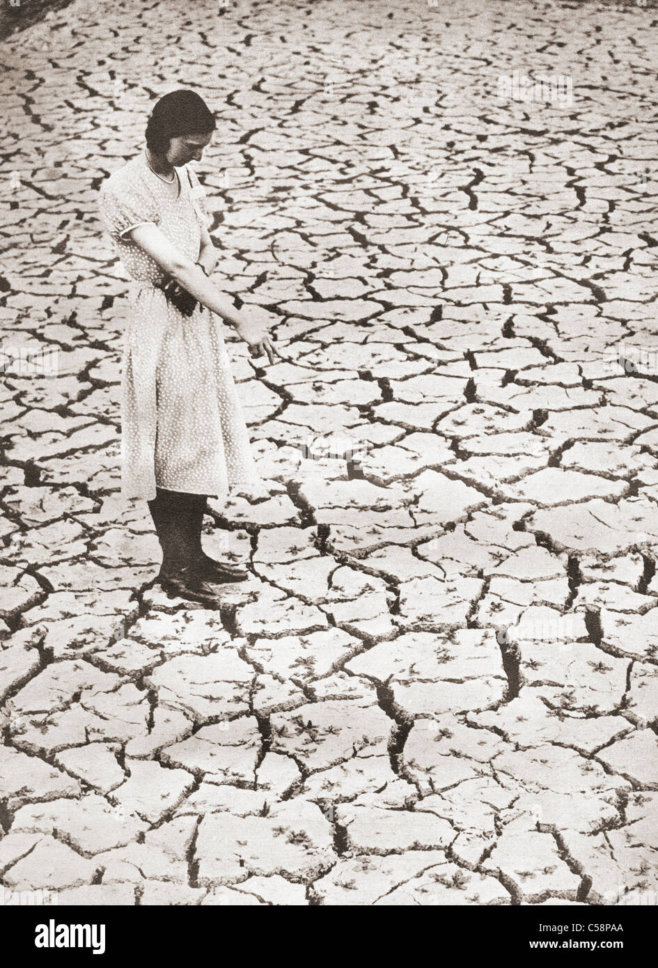 A woman stands looking at the parched ground at The Tring Reservoir, Tring, Hertfordshire, England during the drought of 1934. Stock Photo