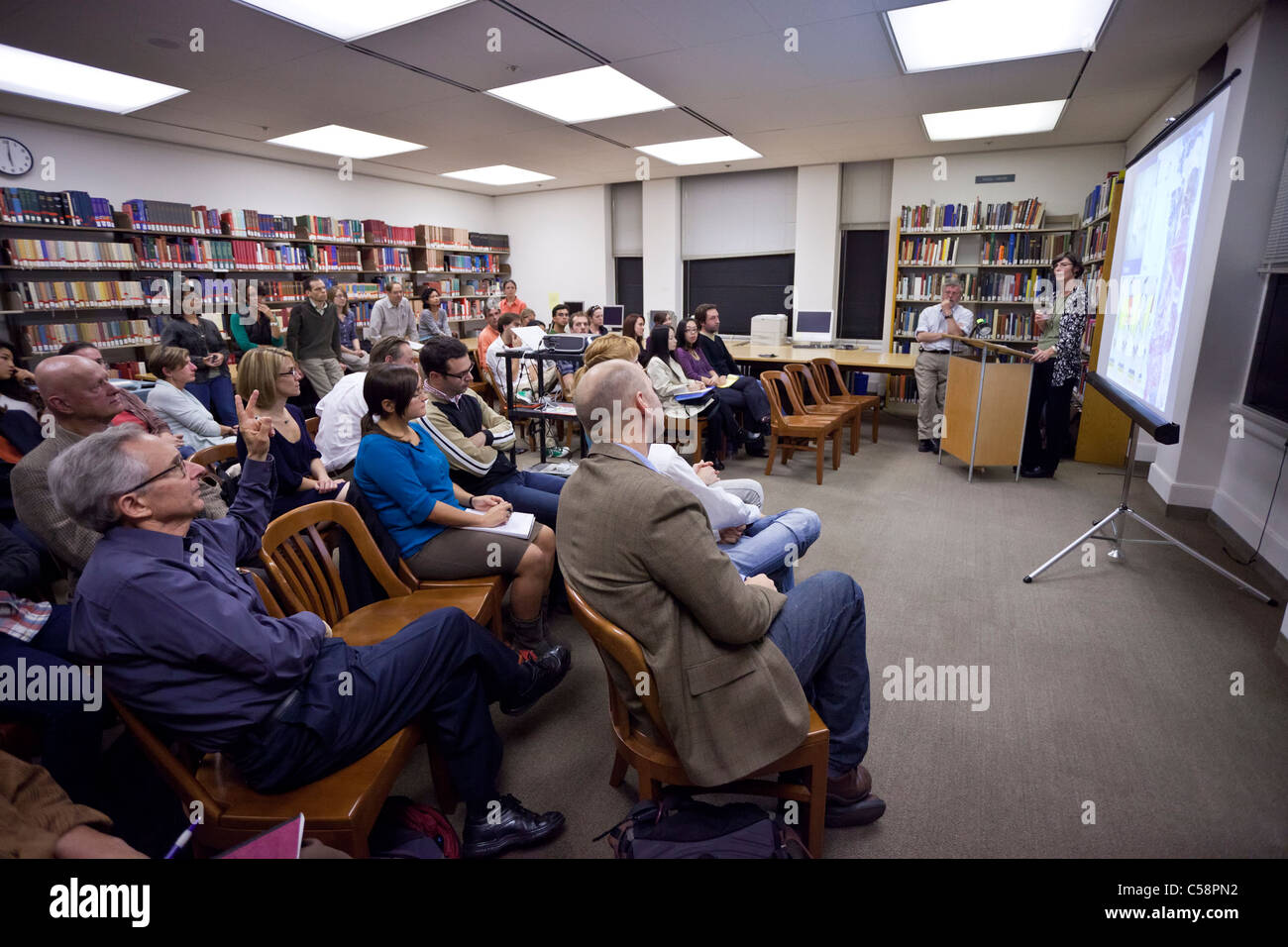 A professor takes questions from a college audience after a lecture. Stock Photo