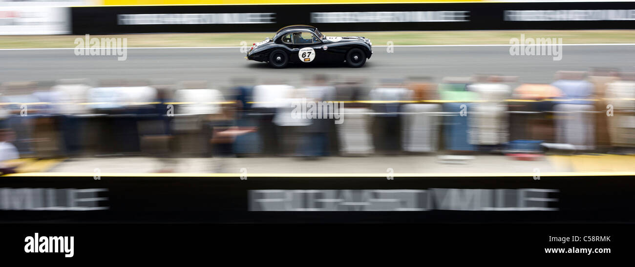 An old classic speeds past the crowds on the pit wall. Le Mans Classic Car Race. France Stock