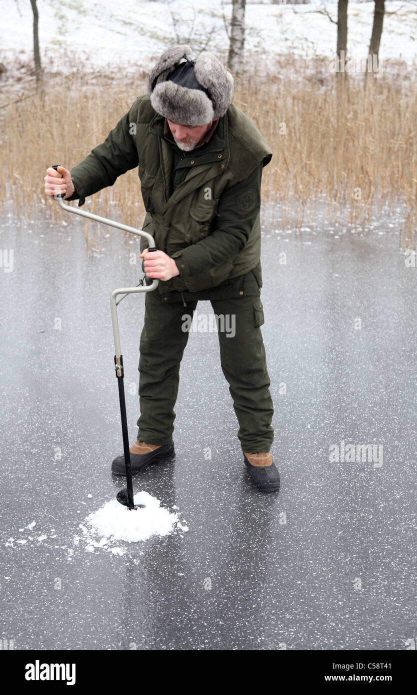 A man drilling an ice-fishing hole in the Stora Bellen lake, Belloe, Sweden Stock Photo