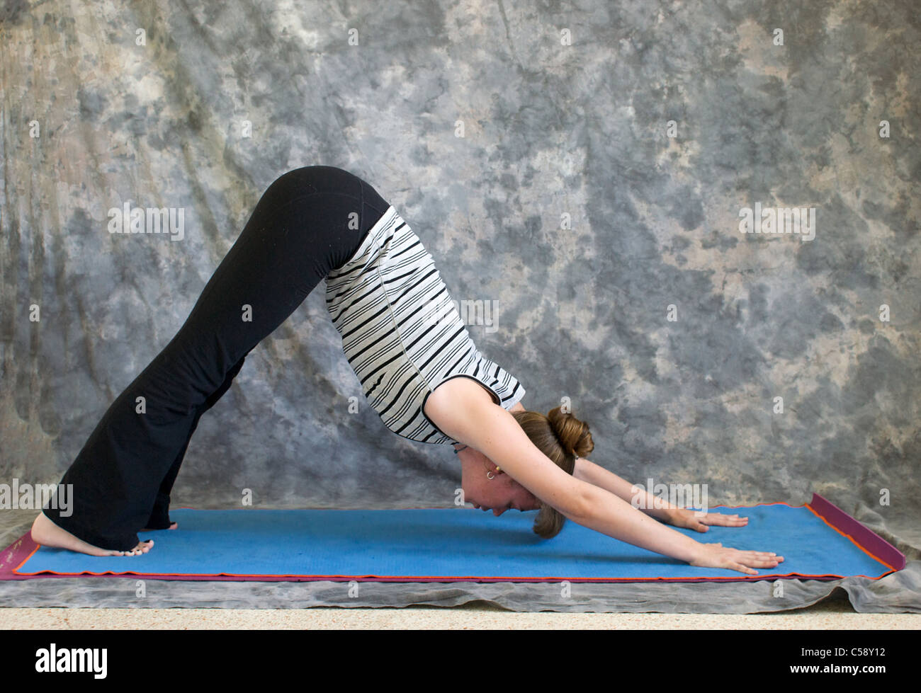 Young woman on yoga mat doing Yoga posture Adho Mukha Svanasana or