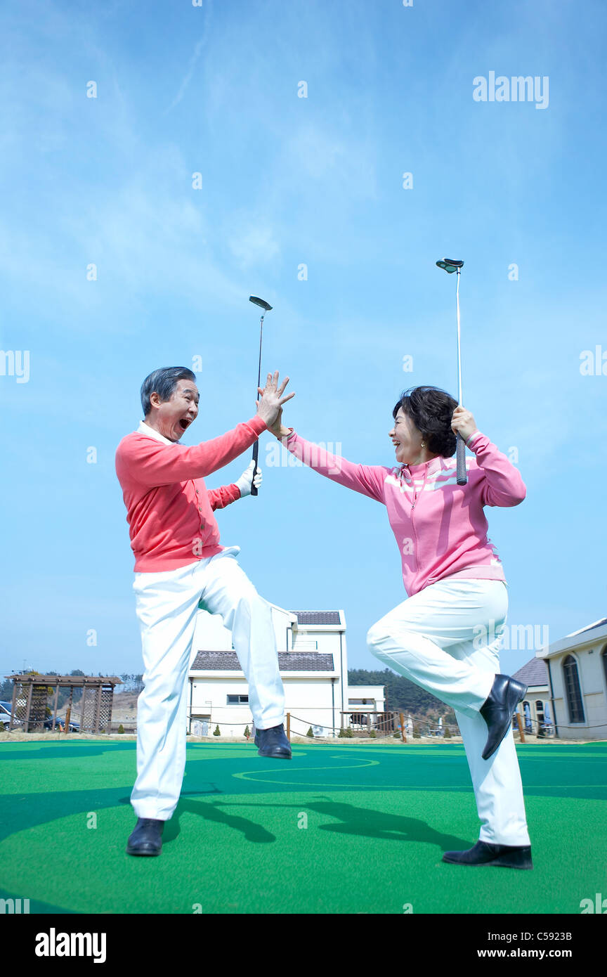 Senior couple jumping on golf course Stock Photo