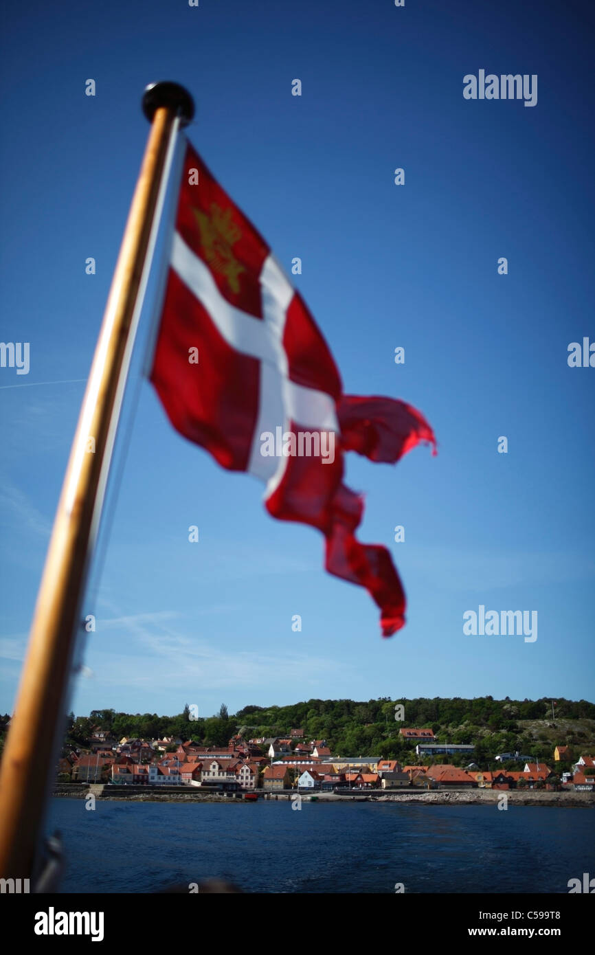 Danish flag over water at Gudhjem, sailing to Christiansø Stock Photo