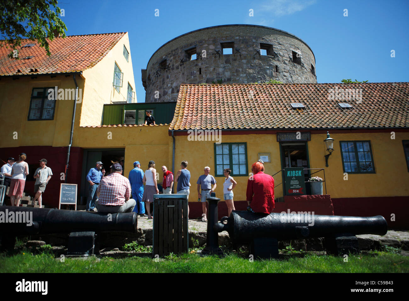 Tourists on Christians Island (Christiansø) with the 17th century 'Great Tower' (Storetårn) behind Stock Photo