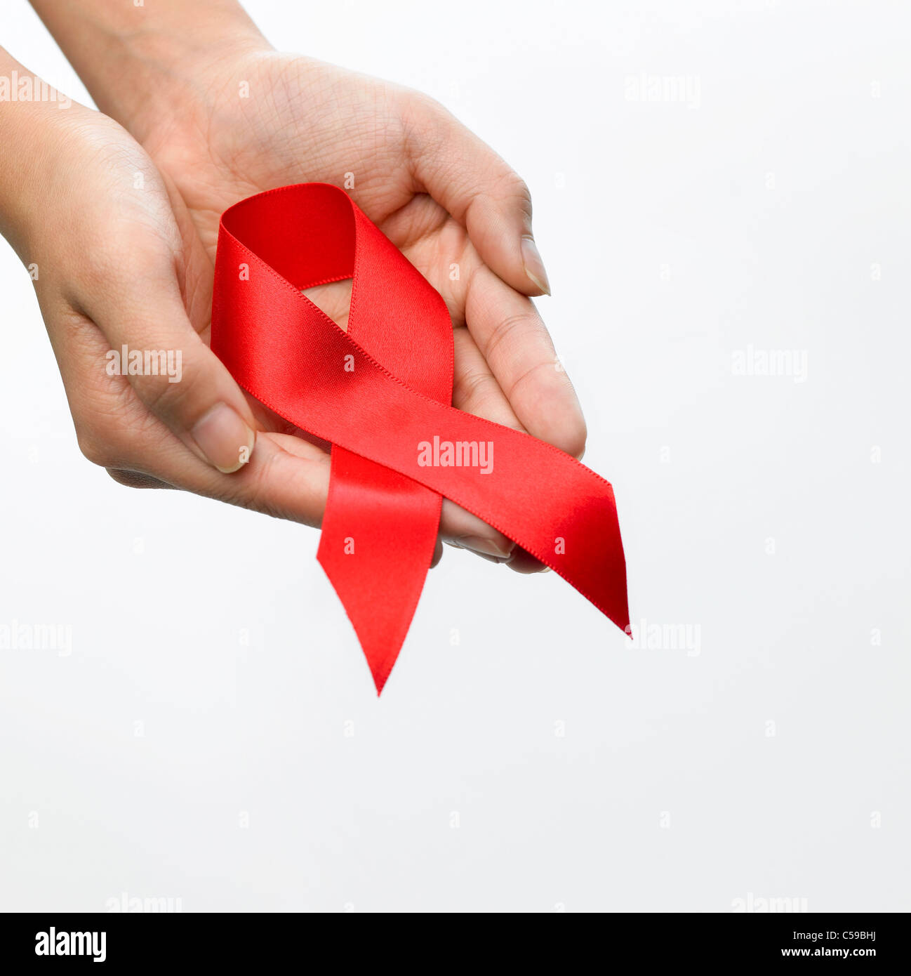 Close-up of person's hand holding red ribbon the AIDS symbol Stock ...