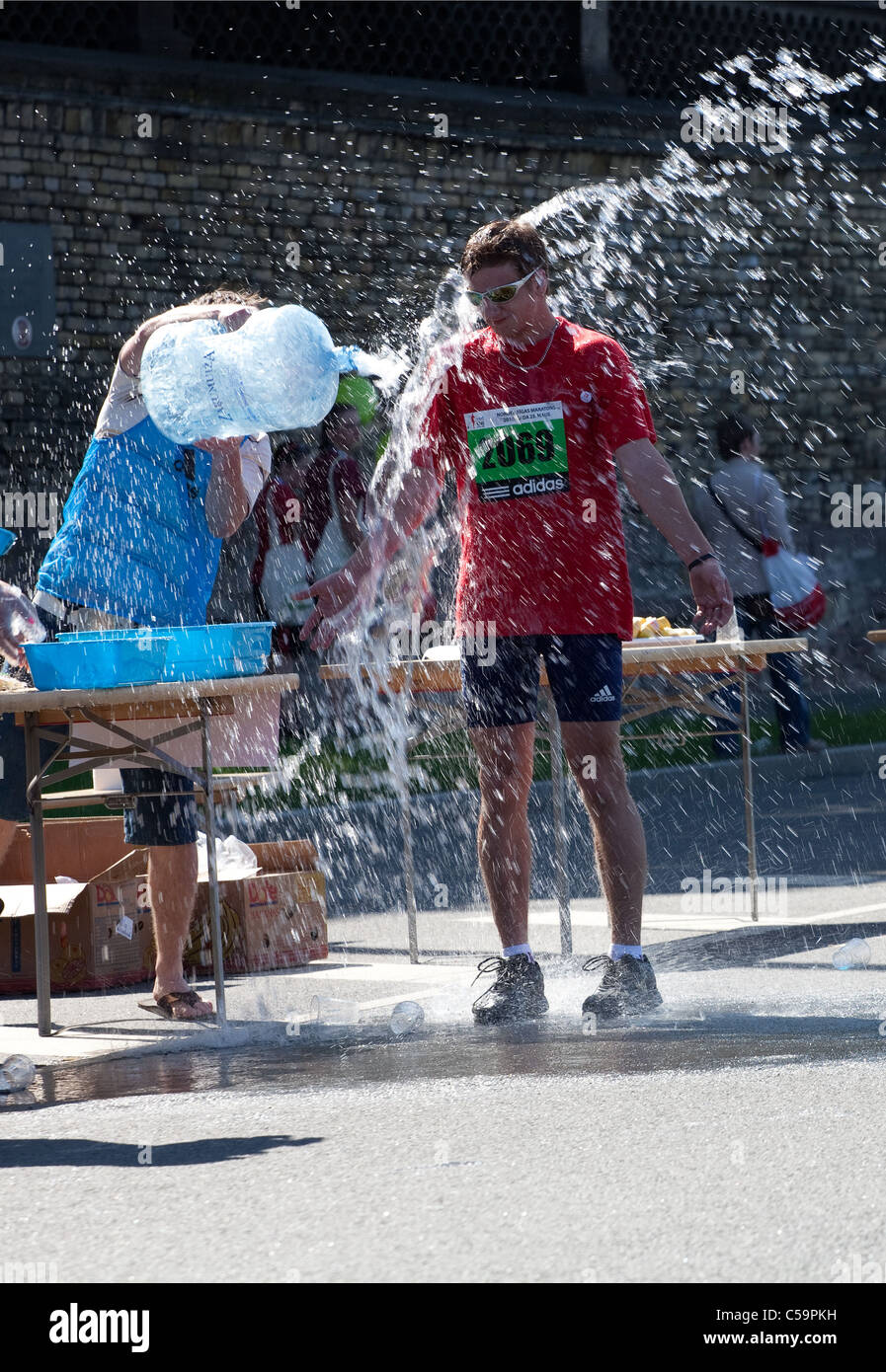 Runner of Riga International Marathon take refreshing water shower on May  23, 2010 Stock Photo - Alamy