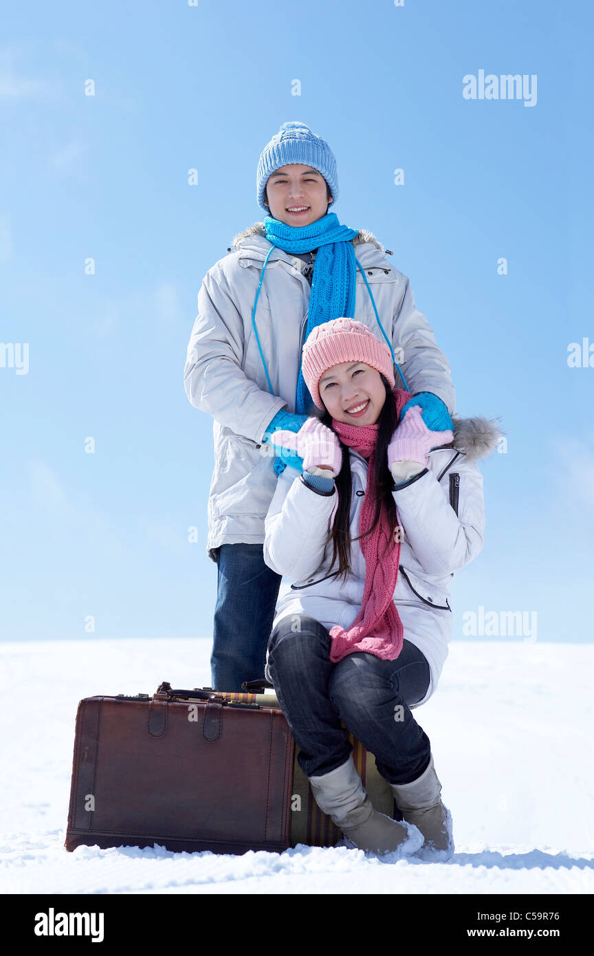 Portrait of man and woman with luggage on snowcapped land Stock Photo ...