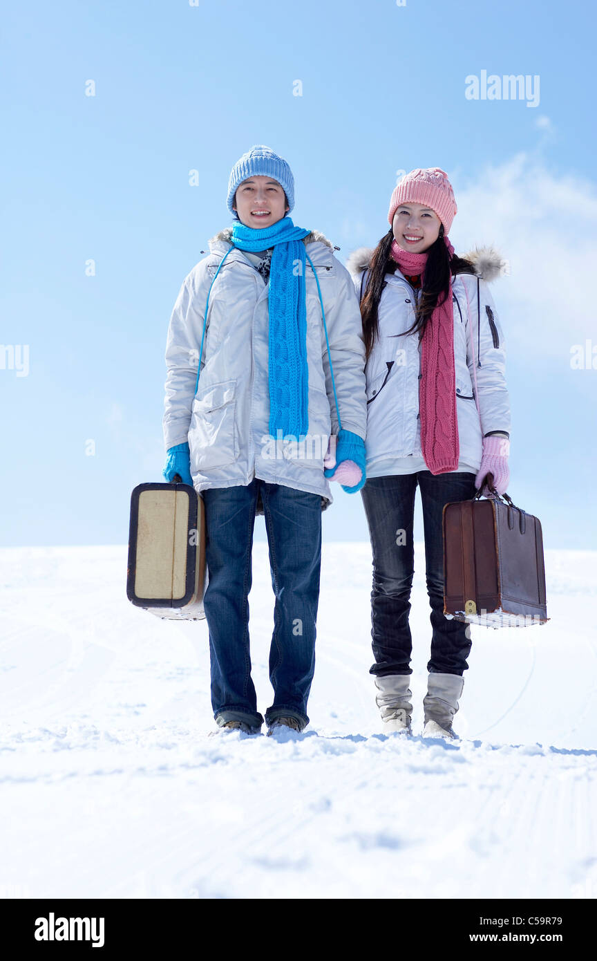 Portrait of man and woman with luggage on snowcapped land Stock Photo ...