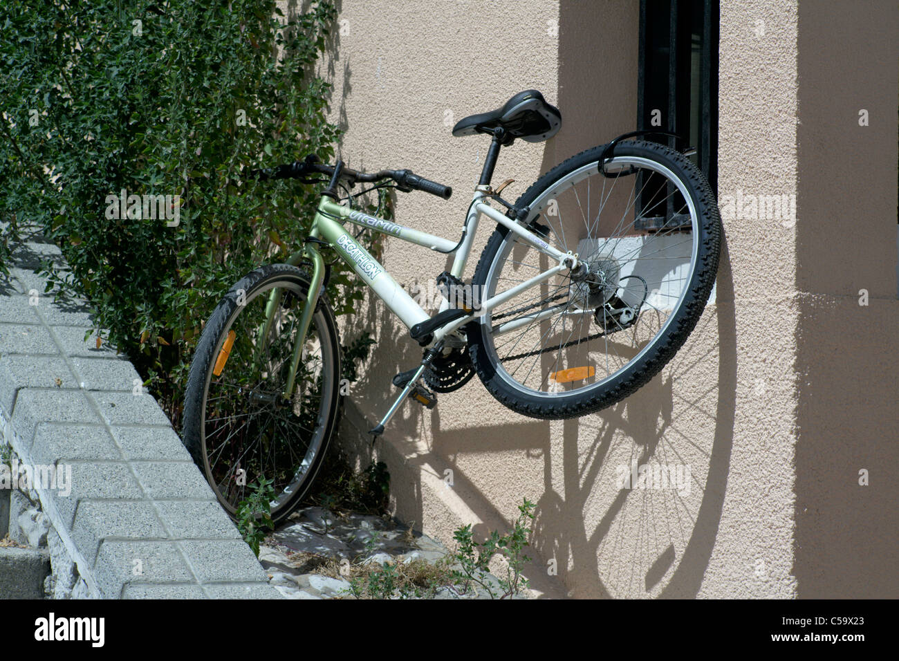 Bicycle chained to window bars in bright sunlight Stock Photo