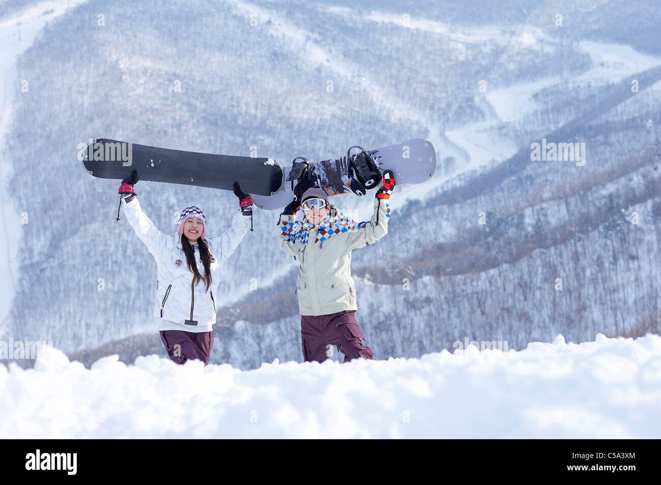 Portrait of young man and woman standing on snowcapped land, holding ...
