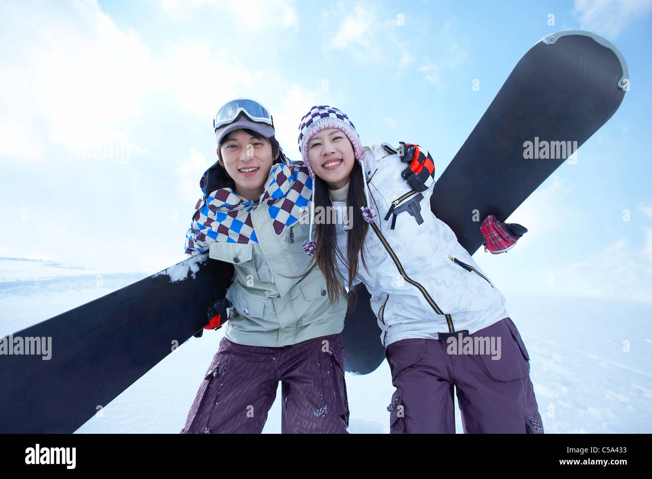 Portrait of young man and woman standing on snowcapped land, holding ...