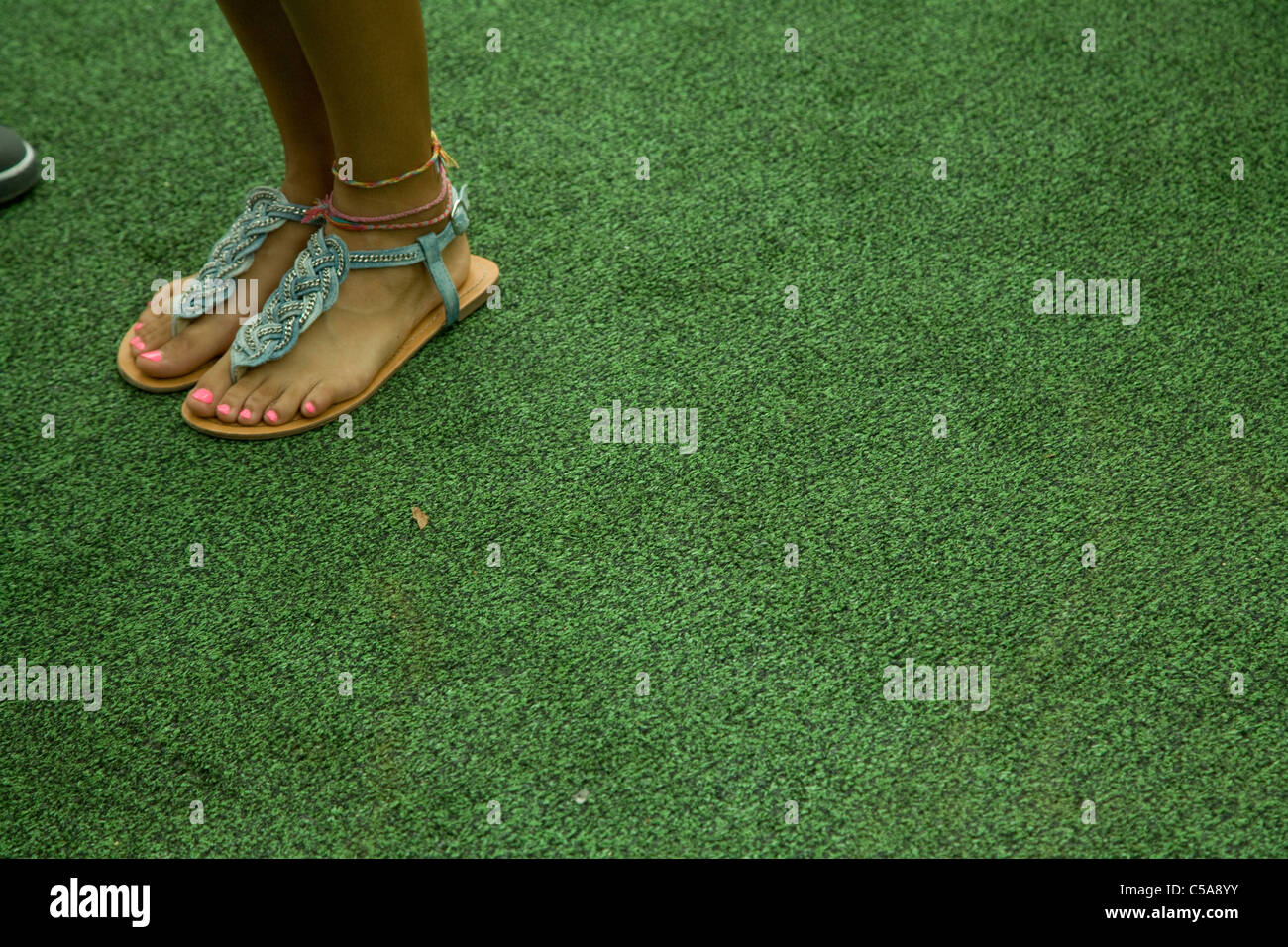 Pink nail polish, on feet of young woman wearing ankle bracelets and