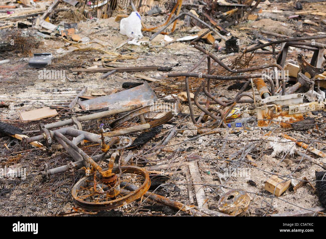 Various objects, including a bicycle, lying in the ashes after a fire. Stock Photo