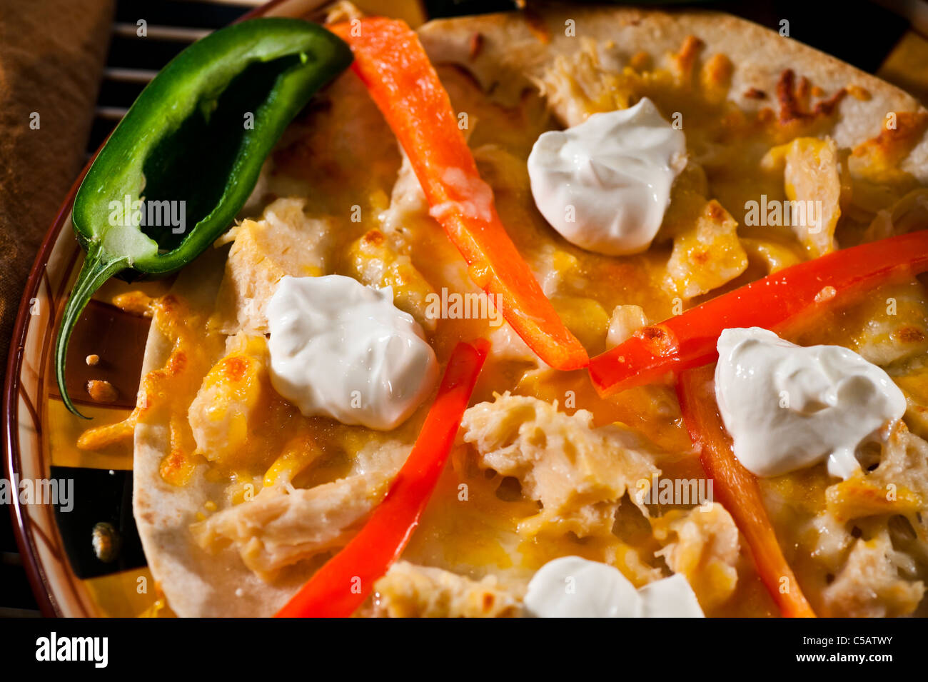 Fresh flour tortilla covered with Cheddar cheese and chicken chunks and peppers. Stock Photo
