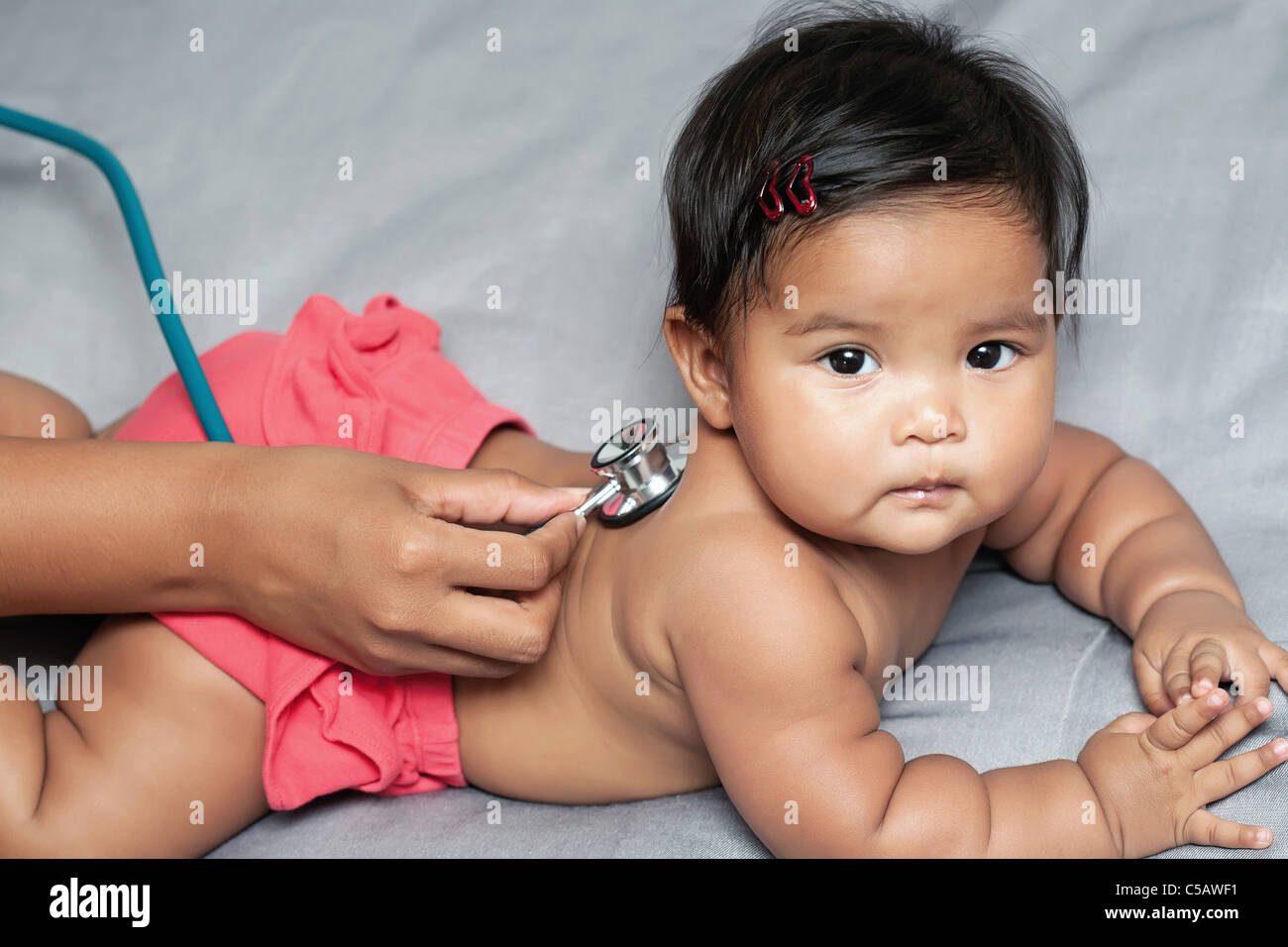 Baby girl laying on her belly, nurse's hand holding stethoscope