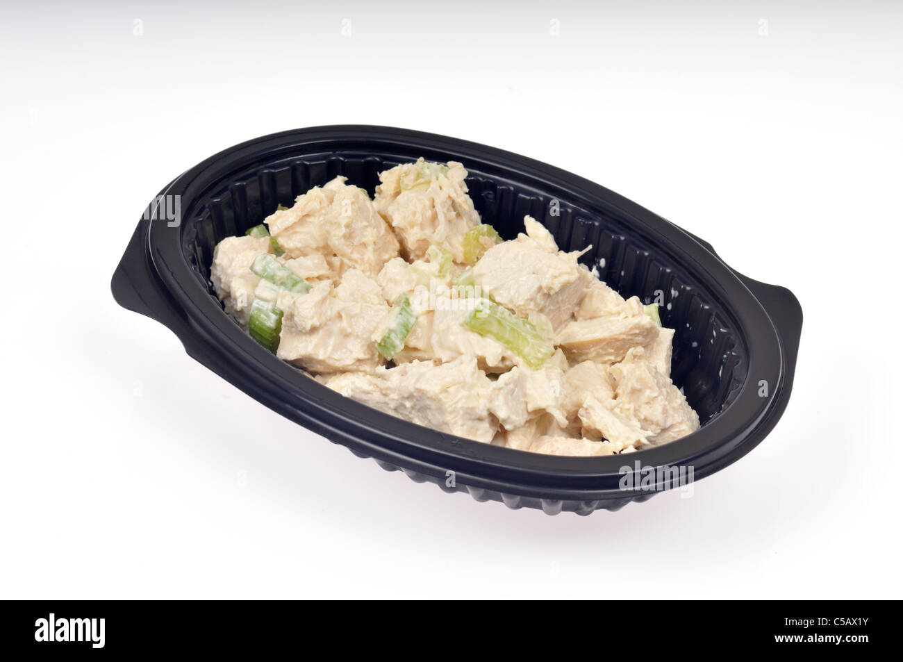 Chicken salad with celery in a black plastic takeaway dish on white background, isolated. Stock Photo