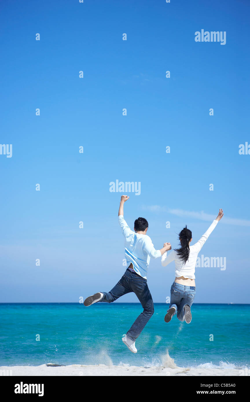 Rear view of Couple Jumping on the sea Stock Photo
