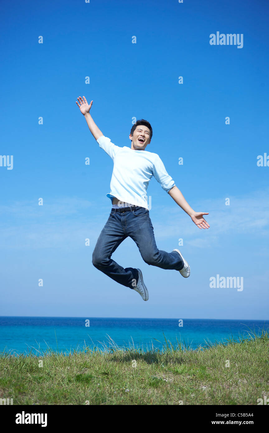 Young man Jumping by sea Stock Photo