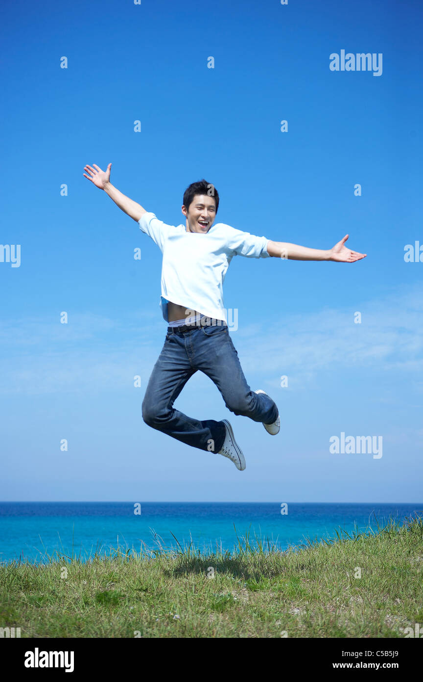 Young man Jumping by sea, Stock Photo